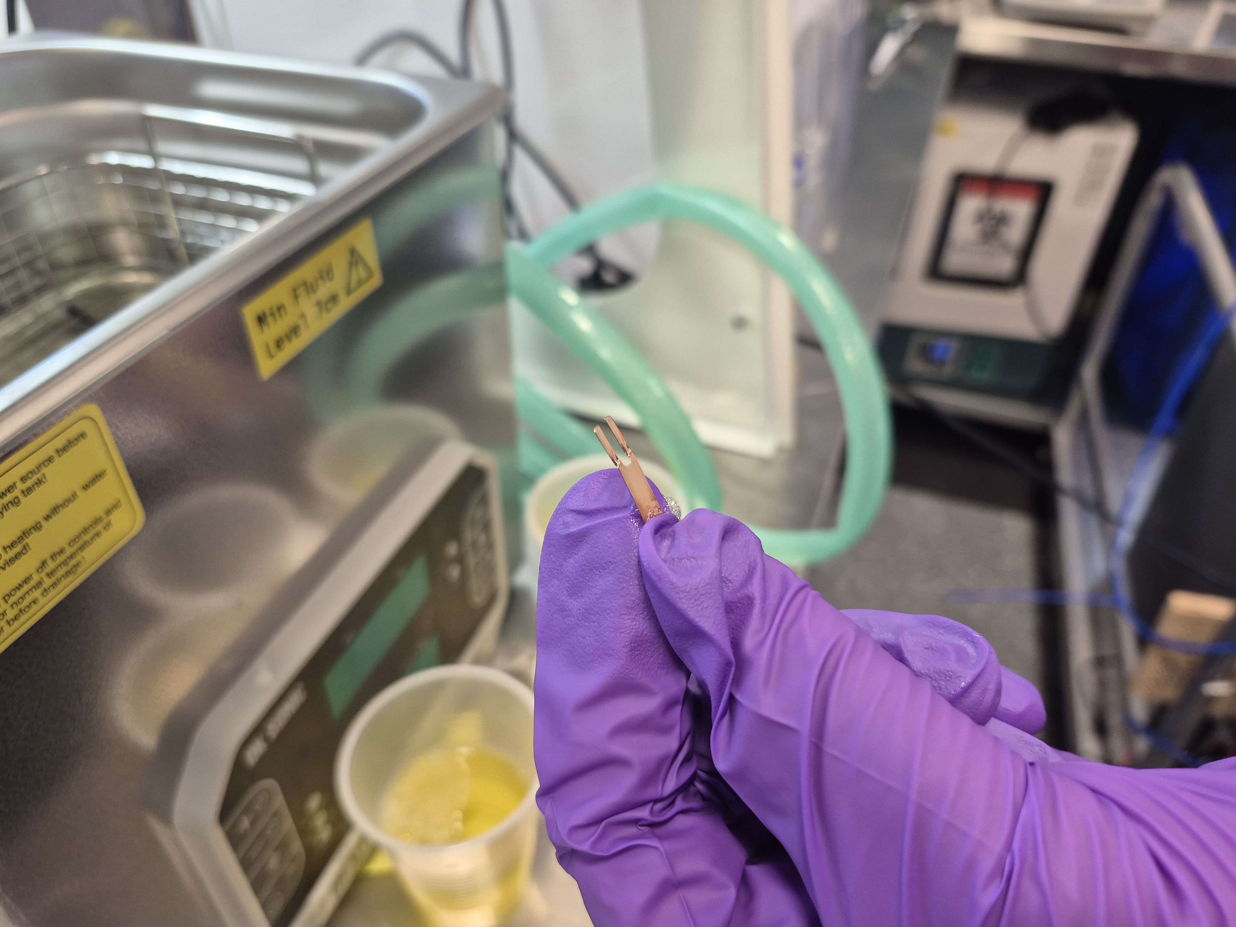 a gloved hand holding a small part with minor bubbles visible